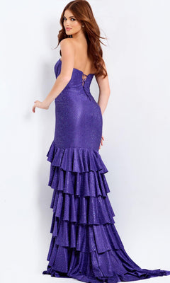 A woman models the Jovani 46909 long prom dress, featuring a backless design, sparkling details, and a tiered ruffle skirt in purple, standing against a plain white background.