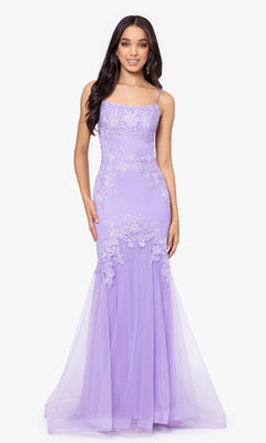 A woman in the Blondie Nites Lilac Purple Long Prom Dress 4706BN, featuring lace appliqué and thin straps, stands against a white backdrop.