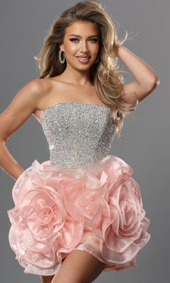 A woman poses with one hand in her hair against a gray background wearing the Jovani 47116 short homecoming dress in blush, featuring a strapless crystal-embellished bodice and a mini skirt adorned with dramatic 3D floral organza rosettes.