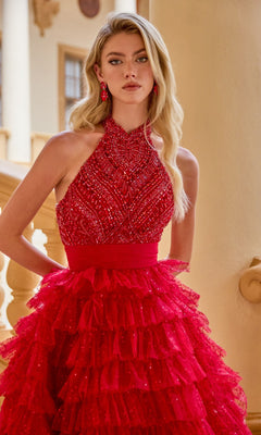 A woman in the Ava Presley 47258 long prom dress, featuring a sleeveless beaded halter bodice and tiered full skirt, stands indoors by a yellow railing.