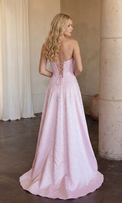 A woman with long blonde hair wears the Ava Presley 47283 Strapless Long Pearl Prom Dress, featuring a lace-up back. She stands indoors beside a pillar and white curtains.