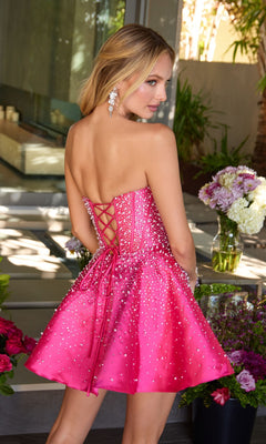 Wearing the Ava Presley 47291 short cocktail dress, a woman stands outdoors near flowers, facing away. The strapless satin dress features a corset bodice and beaded embellishments.