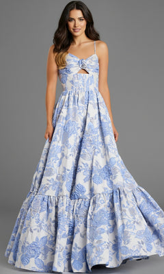 A woman stands against a plain gray background wearing the Jovani 47328 long prom dress, featuring a sleeveless floral jacquard design with blue patterns and an elegant A-line skirt.
