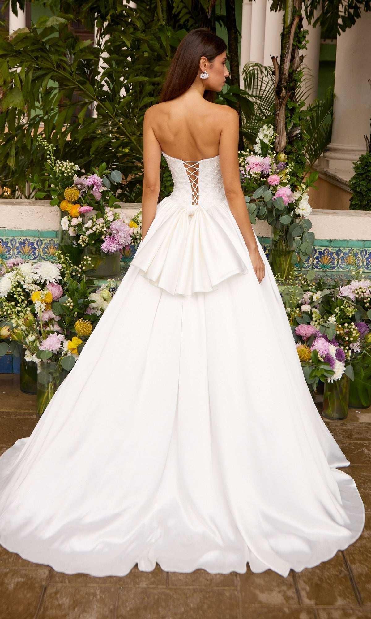 Back view of the Long Prom Dress: Ava Presley 47364, a strapless white floor-length ball gown featuring a lace-up corset back and a waist bow.