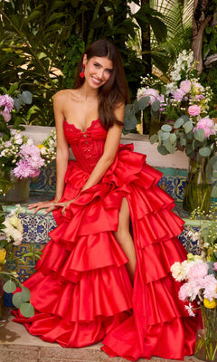 A woman sitting among floral arrangements wearing a red strapless Long Prom Dress: Ava Presley 47372, featuring a tiered ruffled skirt and a high leg slit.