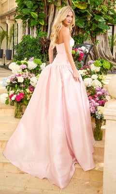 A light pink Ava Presley 47374 strapless floor-length prom ball gown with a full skirt, shown from behind on a stone staircase surrounded by flower arrangements.