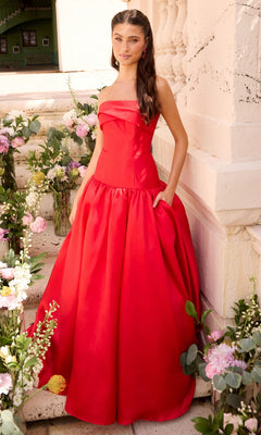 A woman wears a minimalist Long Prom Dress: Ava Presley 47374, a strapless red ballgown with a full skirt and pockets.