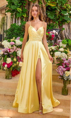 A person wears a soft yellow, sparkly Long Prom Dress: Ava Presley 47403 with a sequined bodice and a high leg slit, standing amidst vases of flowers.