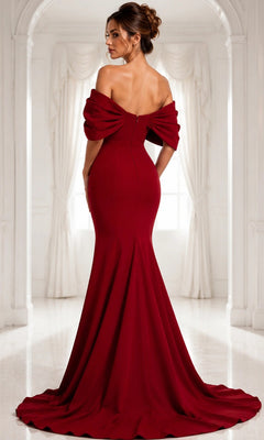 A woman wearing the Long Formal Dress: Jovani 47657, an elegant off-the-shoulder gown, stands with her back to the camera in a white room decorated with arched windows and graceful curtains.