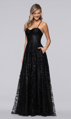 A woman wearing the Long Navy Formal Dress (Blondie Nites 4768BN), a floor-length gown with thin straps and sequin details, stands with one hand in her pocket against a plain background.