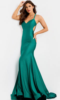 A woman poses in a fitted Jovani 47748 emerald long prom dress with spaghetti straps and a flared hem.
