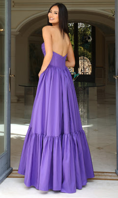 A woman stands indoors before ornate glass doors, wearing the Jovani 47883— a strapless long ruffled prom dress with a sweetheart neckline and corset-style bodice, glancing back over her shoulder.