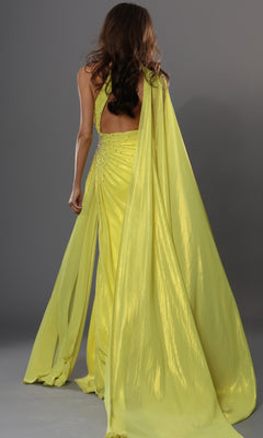 A woman with long brown hair wears the Jovani 48058, a bright yellow, flowing long formal dress featuring a draped train, as she stands against a plain gray background.