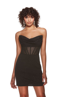 A woman wears the Alyce Off-Shoulder Short Glitter Hoco Dress 4819, featuring a black mini silhouette with a sheer corset bodice and sparkly accents, standing against a white background for a dazzling cocktail look.