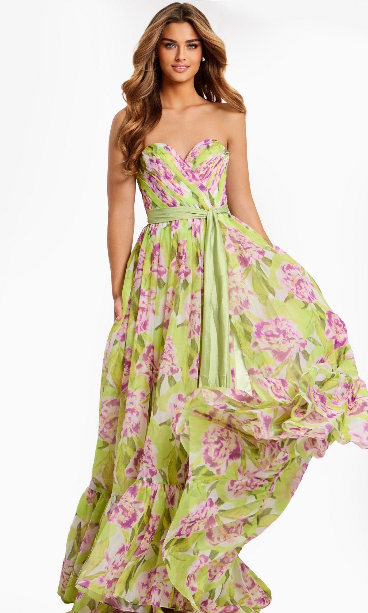 A woman models the Jovani 48468 long prom dress—a strapless gown with a green and pink floral pattern and a green sash—standing against a plain white background.