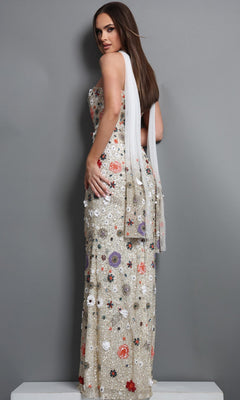 A woman wearing the Jovani 48587 long formal dress—a strapless ivory gown adorned with exquisite floral embroidery—stands on a platform, positioned sideways against a plain gray background.