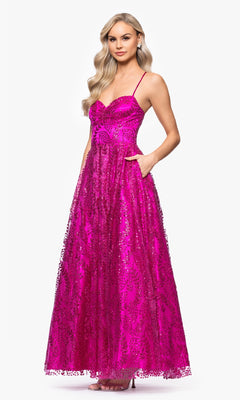 A woman in the Blondie Nites 4867BN long glitter prom dress—a bright pink, sequined, floor-length gown with spaghetti straps—stands facing forward against a plain white background.