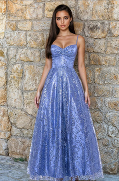 A woman in a budget-friendly, sleeveless periwinkle Long Glitter Prom Dress (Blondie Nites 4867BN) stands before a stone wall.