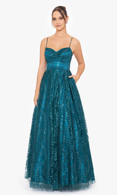 A woman stands against a plain white background wearing the Blondie Nites 4867BN Long Glitter Prom Dress, an affordable teal, floor-length gown with sequins, thin straps, and a sweetheart neckline.