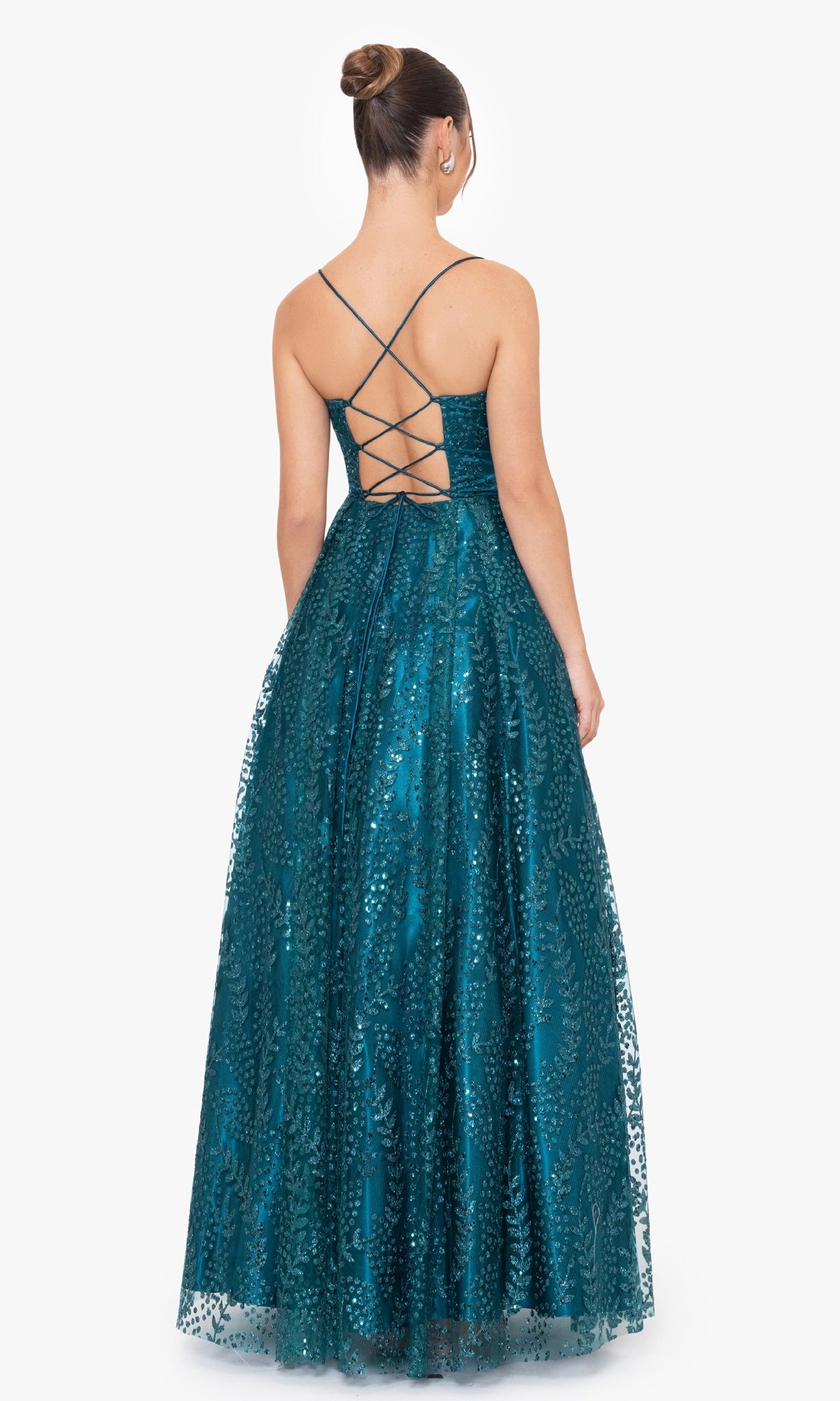 A woman wearing the Blondie Nites 4867BN Long Glitter Prom Dress—a teal, floor-length gown with a lace-up back and sequin details—stands facing away from the camera.