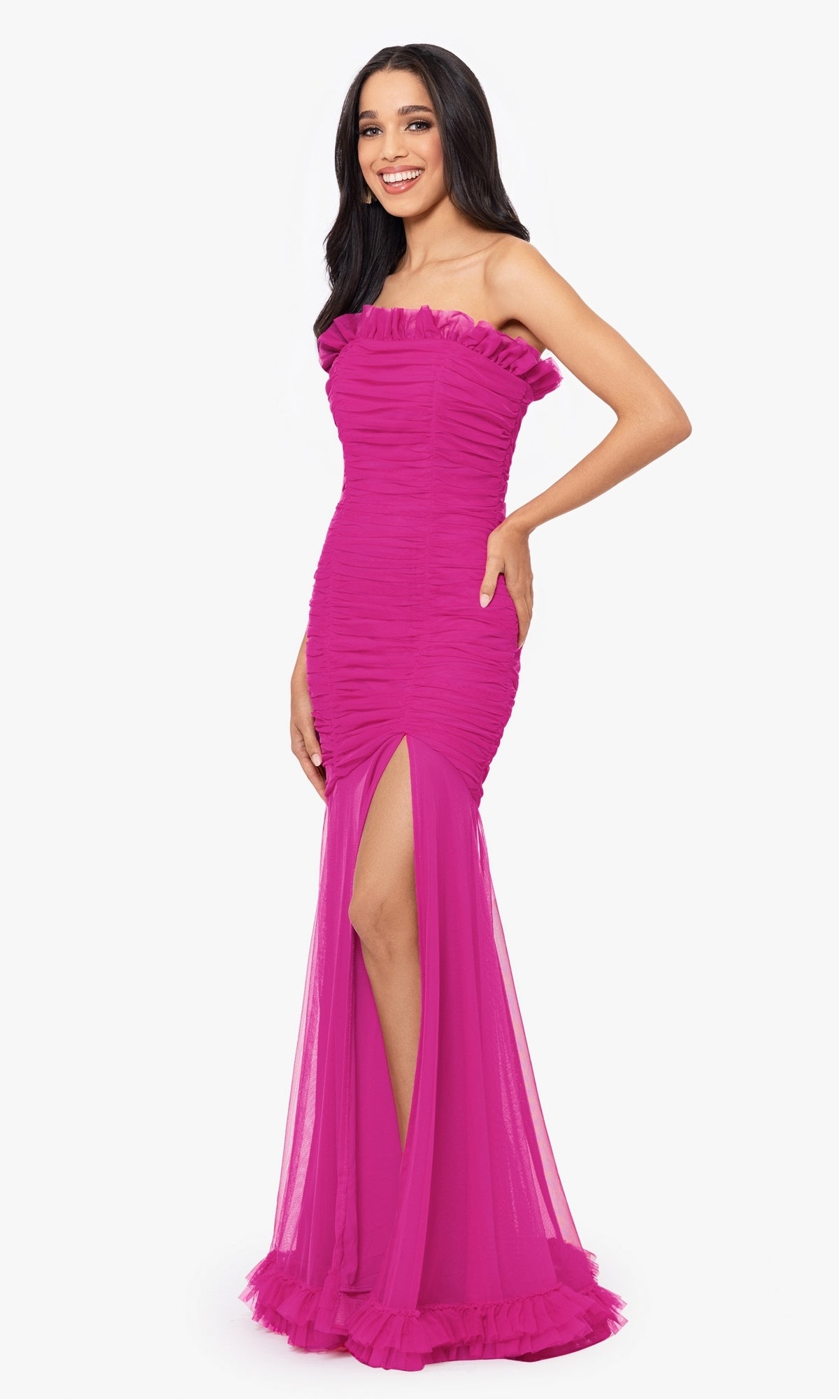 A woman poses against a plain white background in the Hot Pink Strapless Long Prom Dress 4868BN—a junior-size formal gown with a vibrant hue, ruffle details, strapless neckline, and a dramatic thigh-high slit.