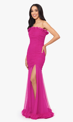 A woman poses against a plain white background in the Hot Pink Strapless Long Prom Dress 4868BN—a junior-size formal gown with a vibrant hue, ruffle details, strapless neckline, and a dramatic thigh-high slit.
