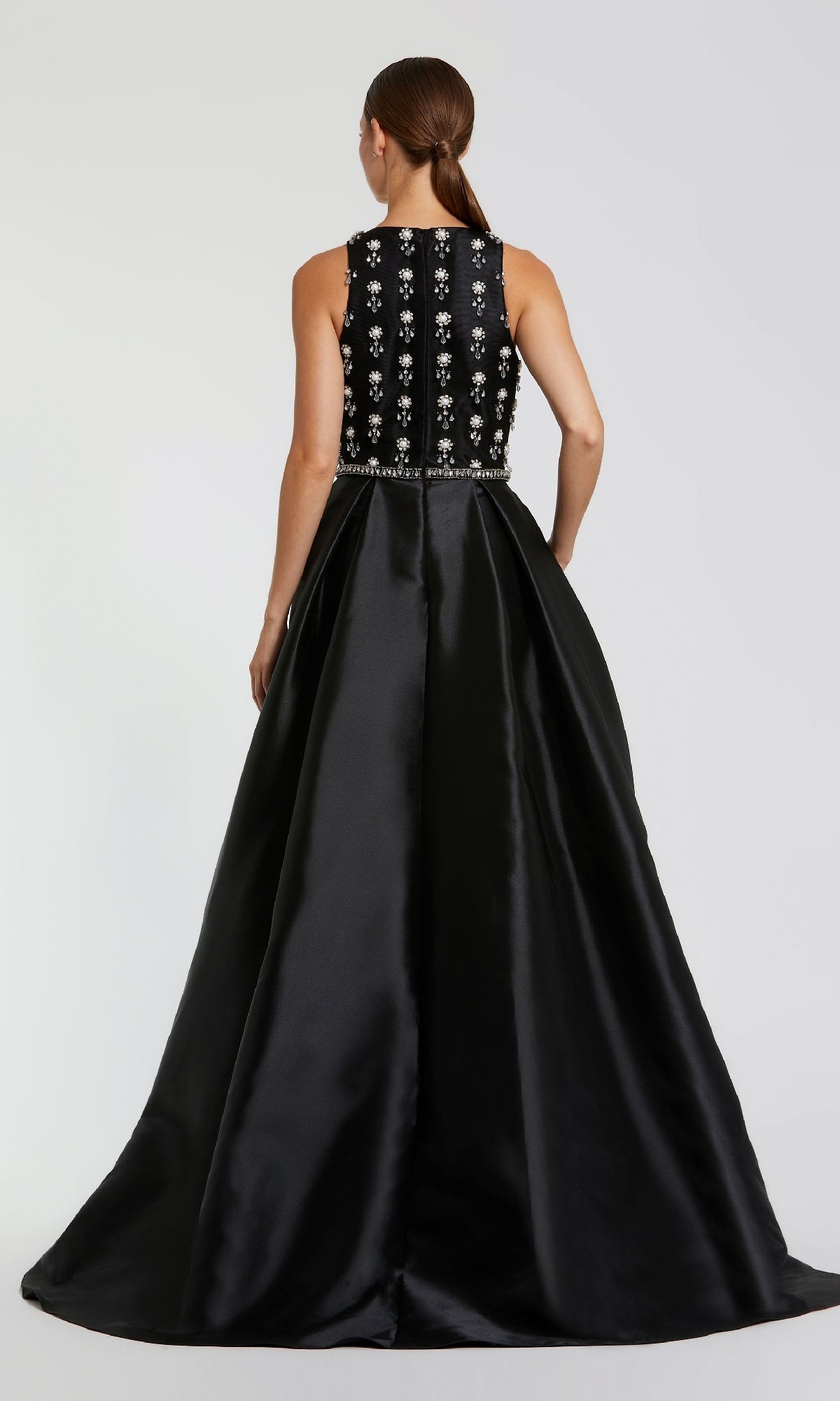 A woman faces away, wearing the Mac Duggal 48803 long formal dress with a sleeveless beaded bodice and flowing satin A-line skirt against a plain background.