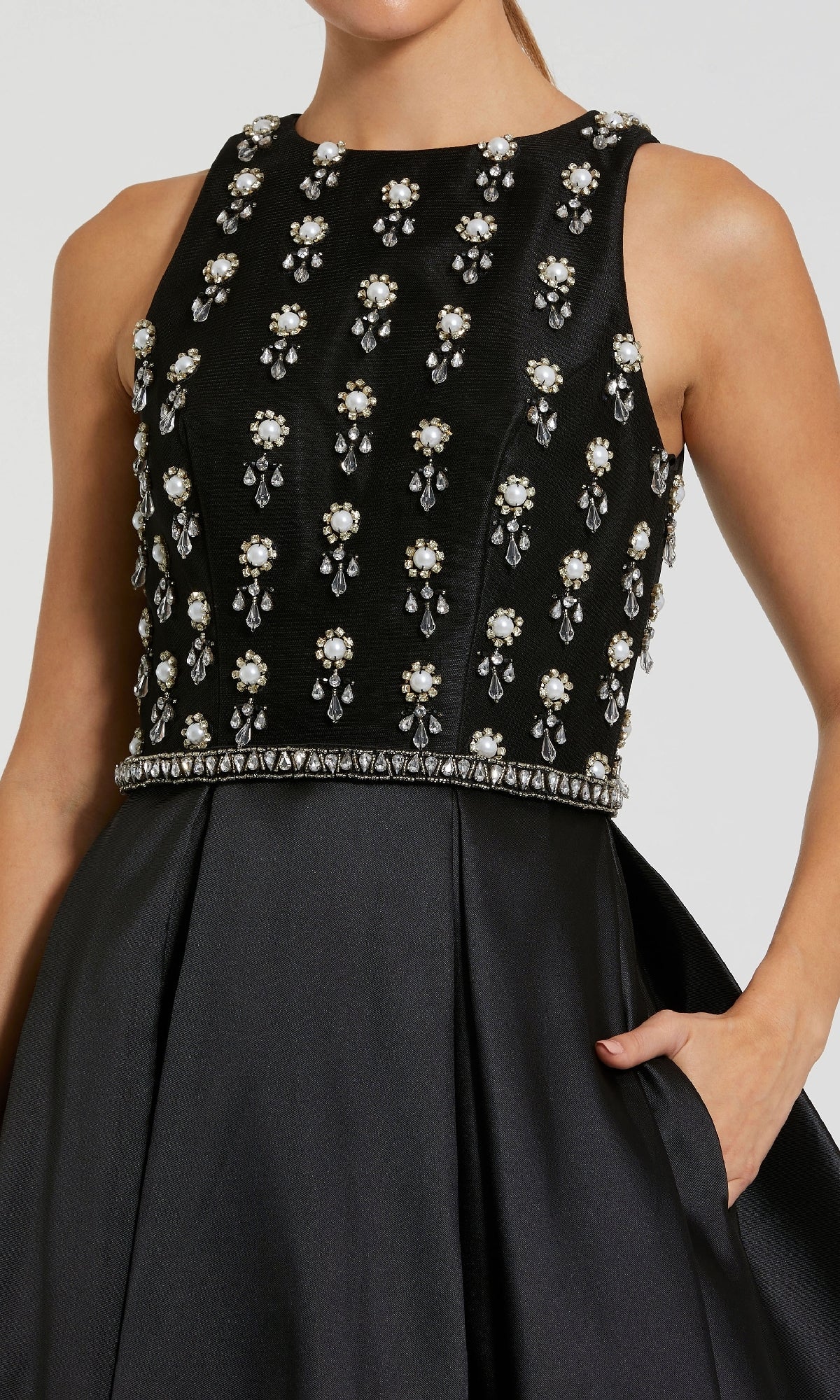Woman in the Mac Duggal 48803 long formal dress with a sleeveless embellished bodice, satin A-line skirt, and one hand in the pocket.