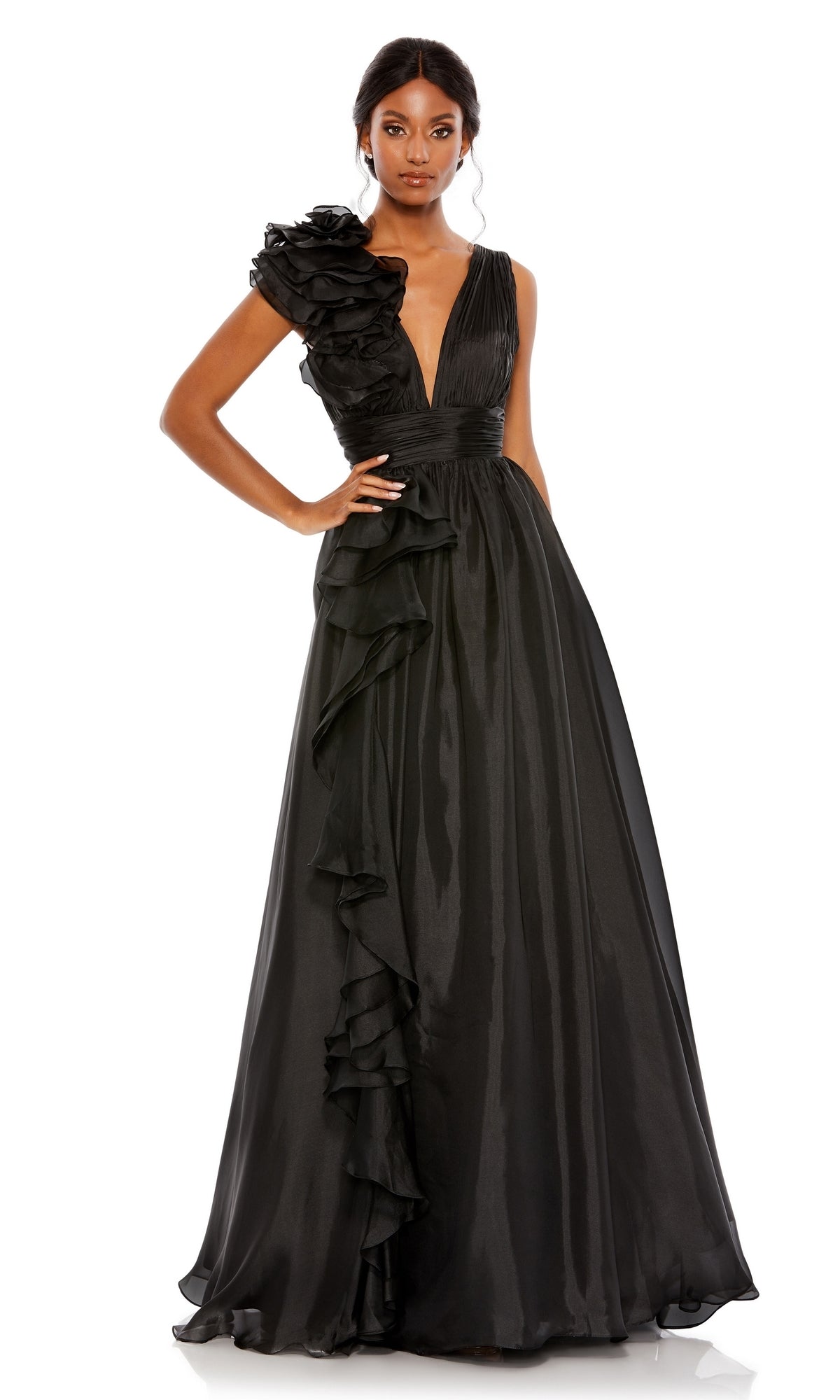 A woman wearing the Mac Duggal 48856 Ruffled Long Prom Ball Gown—a black evening dress with a deep V-neck and ruffled details on one shoulder and along the skirt—stands against a white background.