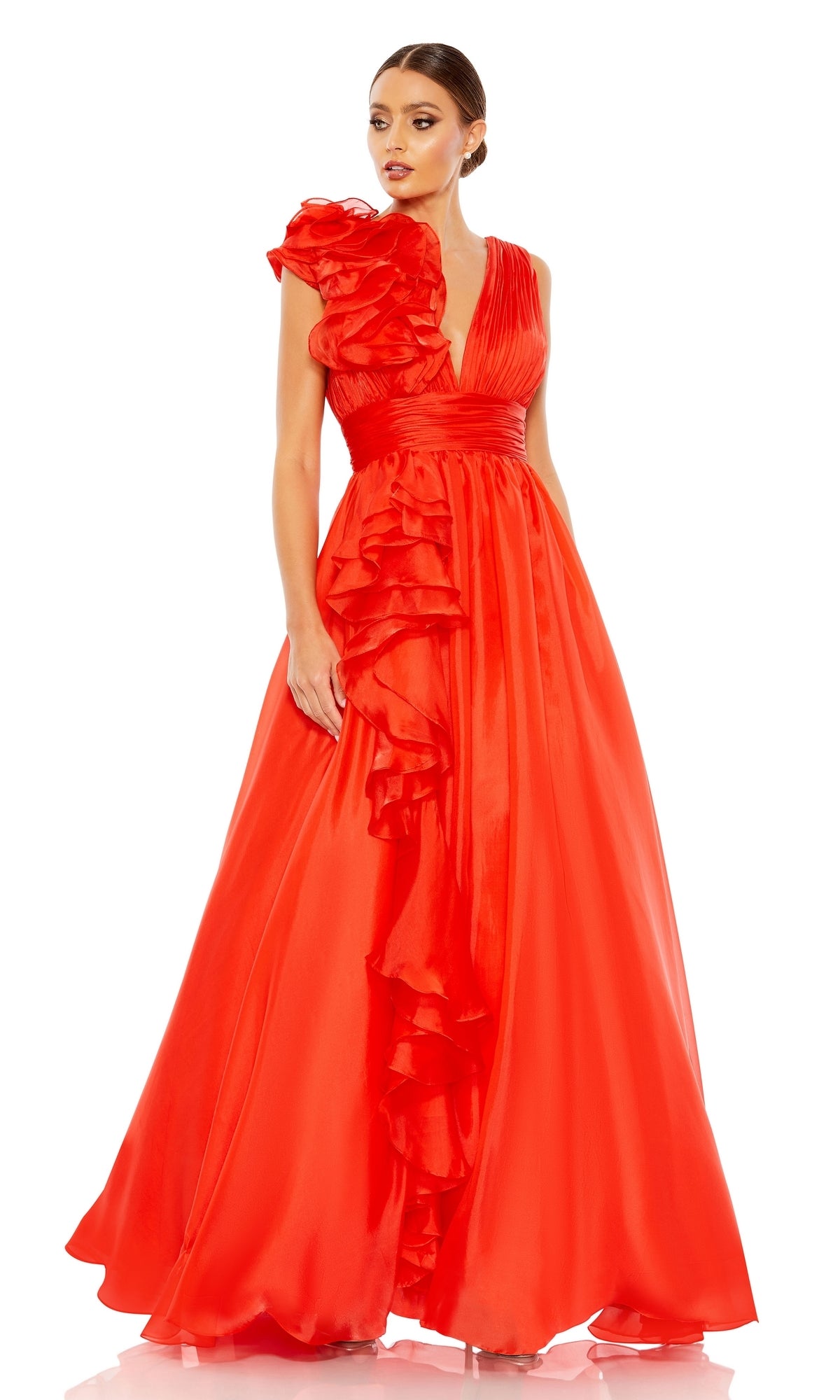 A woman stands against a white background wearing the Mac Duggal 48856 Ruffled Long Prom Ball Gown, a floor-length, bright red dress featuring ruffled details, a deep V-neckline, and a single ruffled shoulder.