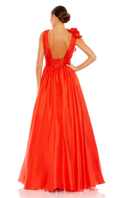 A woman stands with her back to the camera, wearing the Mac Duggal 48856 Ruffled Long Prom Ball Gown—a floor-length, sleeveless red dress featuring an open back and one-shoulder floral detail.