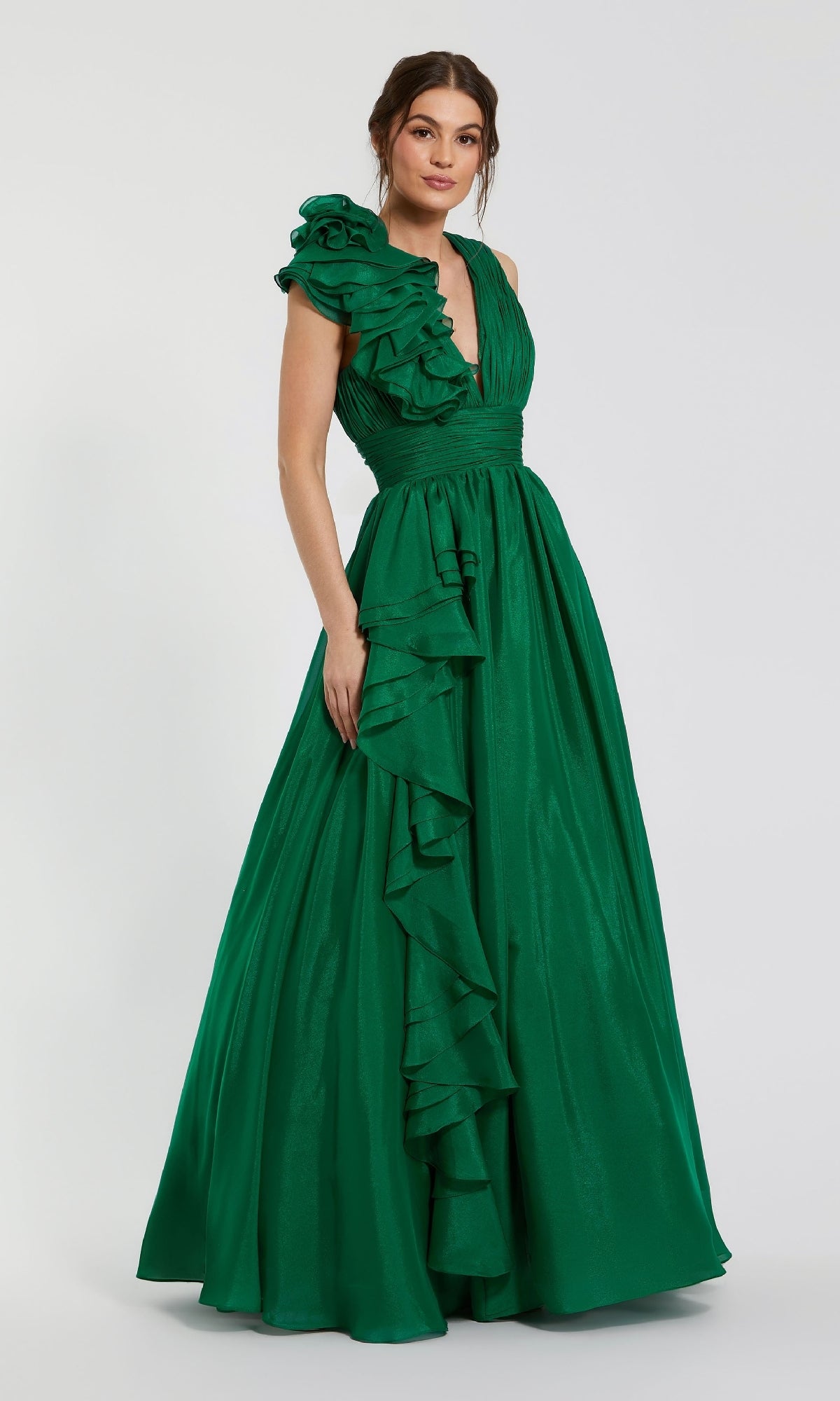 A woman stands against a plain background wearing the Mac Duggal 48856 Ruffled Long Prom Ball Gown—an elegant, sleeveless green dress with ruffle details and a deep V-neckline.