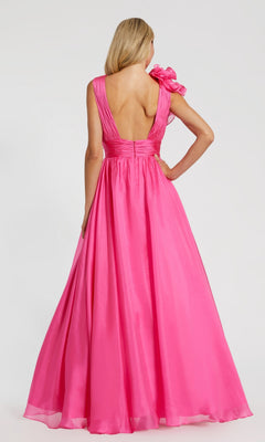 A woman is seen from behind wearing the Mac Duggal 48856 Ruffled Long Prom Ball Gown—a floor-length, bright pink dress with a deep V-back and a dramatic ruffle on one shoulder.