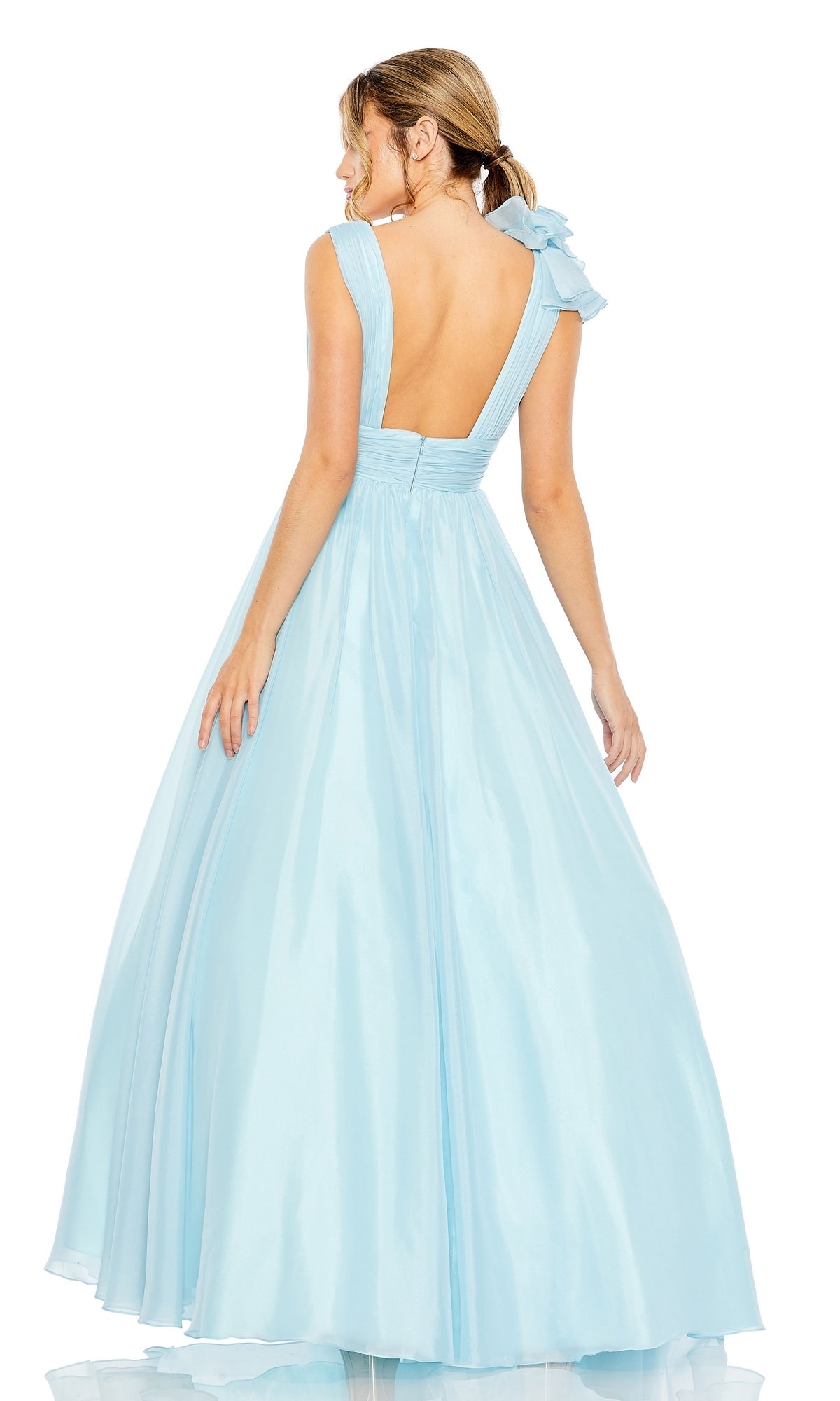 A woman in the Mac Duggal 48856 Ruffled Long Prom Ball Gown, light blue and floor-length, with an A-line silhouette, open back, and bow detail, stands facing away.