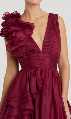 A woman in the Mac Duggal 48856 Ruffled Long Prom Ball Gown, featuring a sleeveless design, deep red color, pleated bodice, and a large ruffled detail on one shoulder.