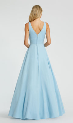 A woman with long blonde hair models the Mac Duggal 48924 Classic Long Prom Ball Gown—a sleeveless, floor-length light blue dress with a V-back and full skirt—against a plain background.
