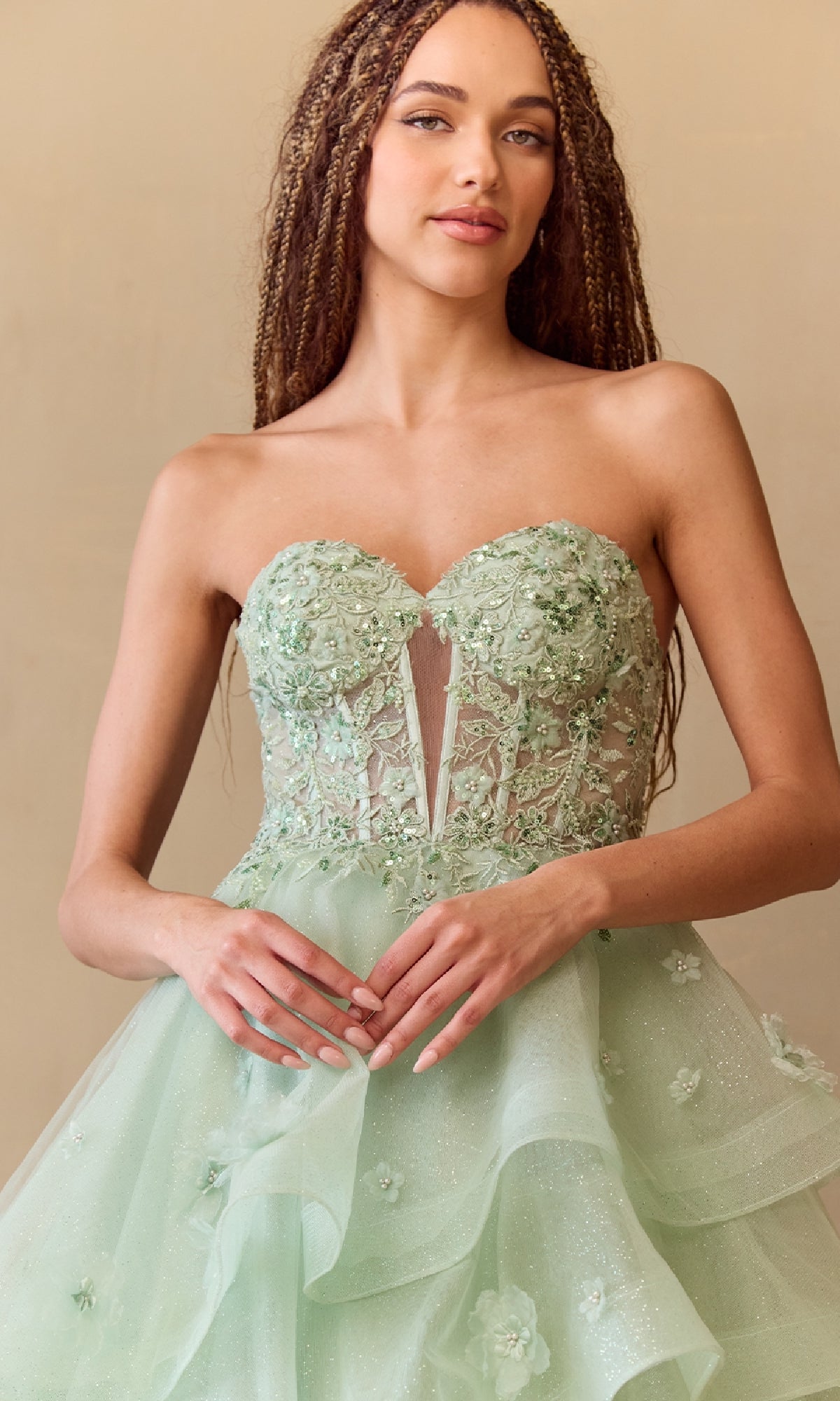Woman wearing a light green strapless dress with floral details against a beige background