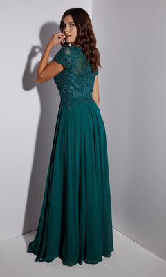 Woman with wavy brown hair wears the Eureka 4909 Short-Sleeve Long A-Line Formal Dress with an embroidered lace bodice, standing in a corner and glancing over her shoulder.
