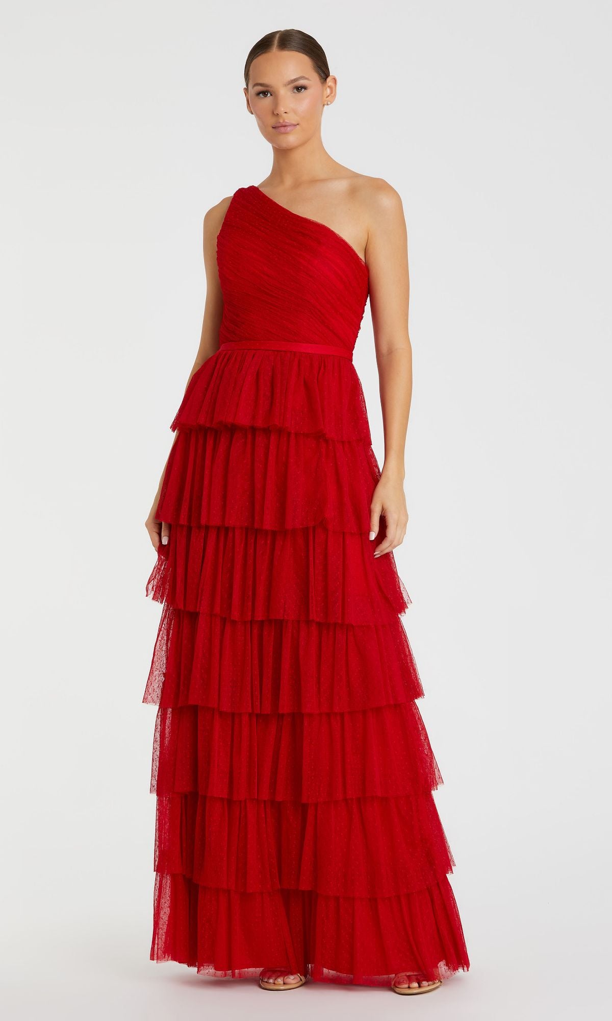 A woman wears the Long Formal Dress 49102 by Mac Duggal, a red one-shoulder gown with multiple tiered ruffles and a banded waist, standing against a plain light background.