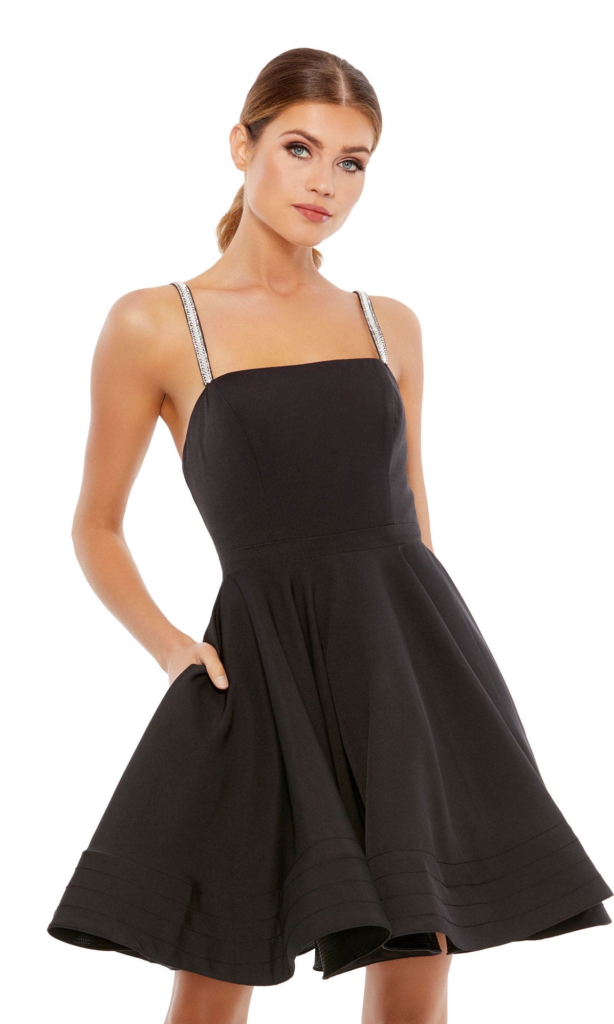 Model wearing the Short Black A-Line Fancy Party Dress 49106 featuring a sleeveless design, flared skirt, silver straps, and handy pockets, posed against a plain white background.