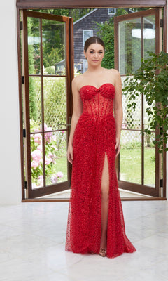 A woman stands indoors in front of open glass doors, wearing the Morilee 49117 Strapless Sequin Prom Dress in Scarlet, featuring a sweetheart neckline and a thigh-high slit, with a garden visible outside.