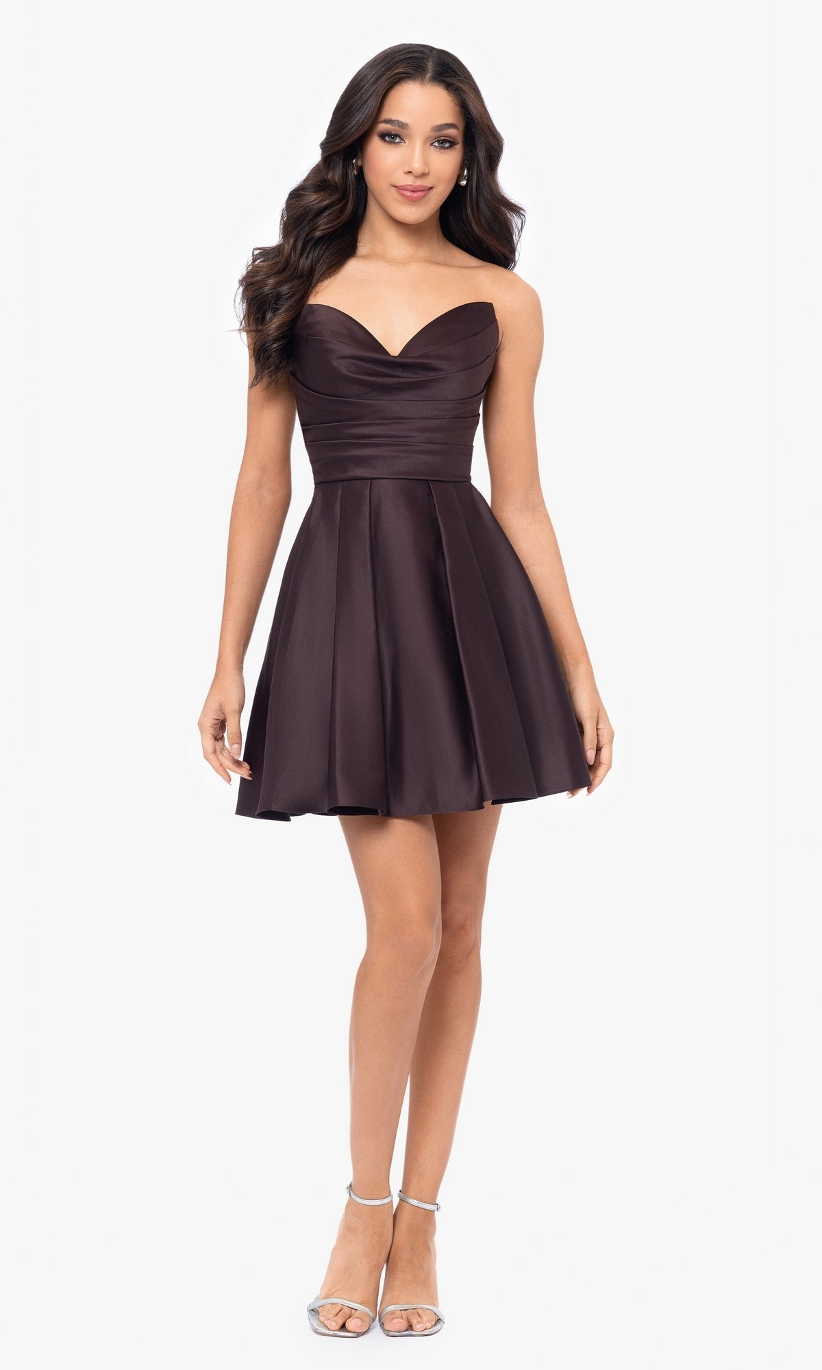 A woman stands facing forward in silver heels, wearing the Short Strapless Sweetheart Hoco Dress 4914BN in dark brown, featuring a fitted bodice, ruched waist, and flared knee-length skirt.