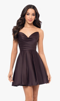 A woman wearing the Short Strapless Sweetheart Hoco Dress 4914BN in dark brown, featuring a ruched waist, stands against a plain white background.