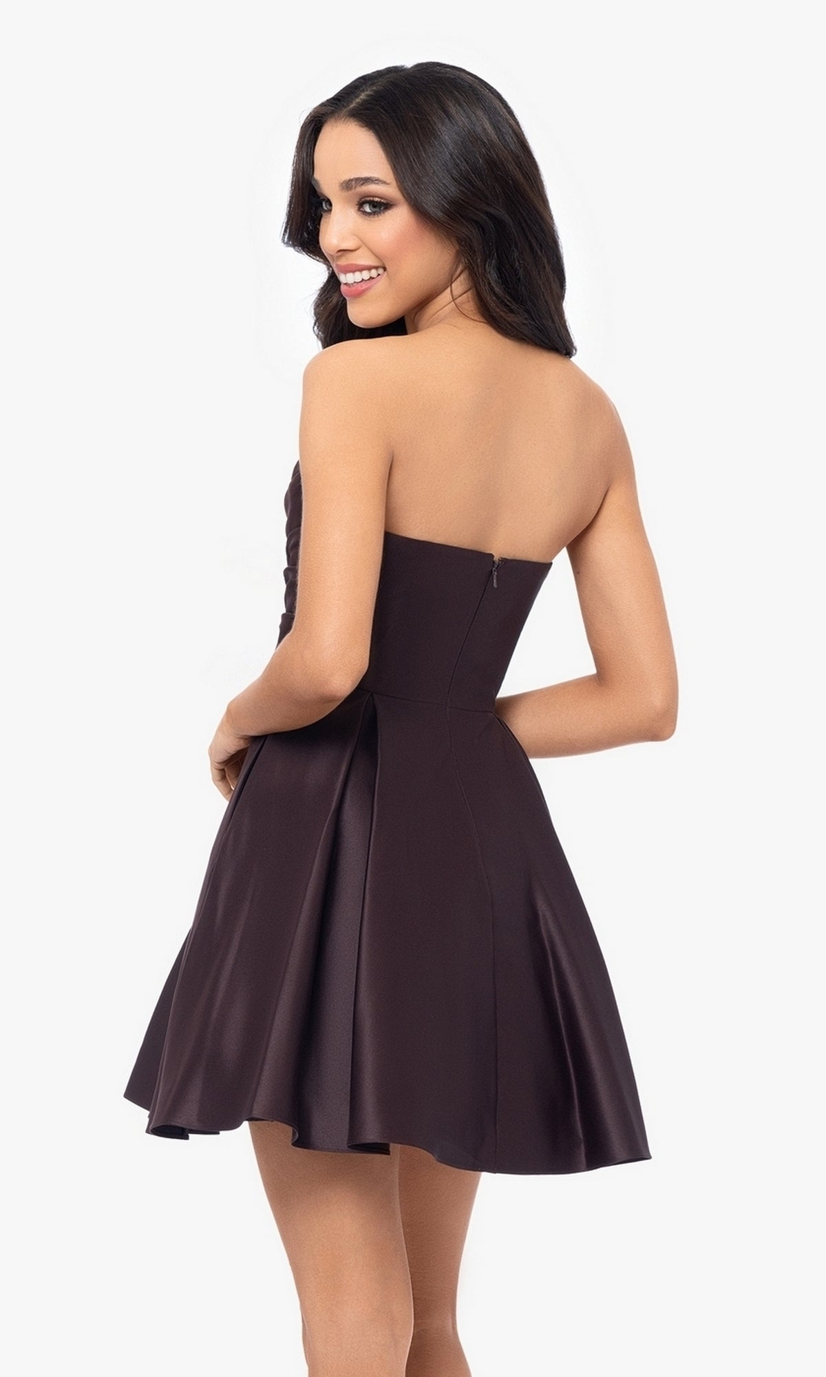 A woman in the Short Strapless Sweetheart Hoco Dress 4914BN—dark purple satin with a ruched waist—stands slightly turned and smiles against a plain white background.