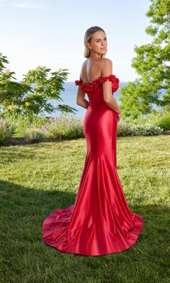 A woman wearing the Morilee 49171 long prom dress, fitted and off-the-shoulder, stands on grass facing away, with trees and water in the background.