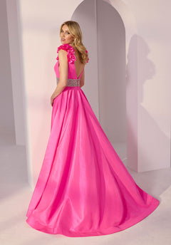 A woman in a bright pink Morilee 49202 long prom dress with ruffled sleeves and a jeweled waistband stands in a minimalist, pale room with arched architecture.