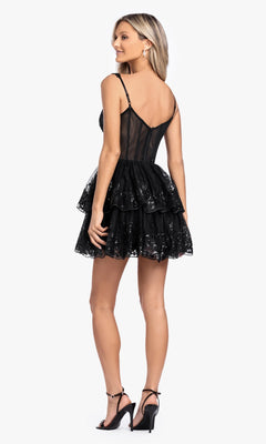 A woman faces away, wearing the Short Ruffled Hoco Dress: Blondie Nites 4931BN—a sleeveless, sequin-embellished black mini dress with tiers and a sheer back—styled with black high-heeled sandals.