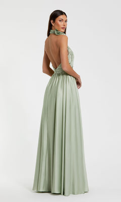 A woman models the High-Neck Halter Formal Dress: Mac Duggal 49333—a light green, backless satin gown—standing against a plain white background and looking over her shoulder to display its elegant silhouette.