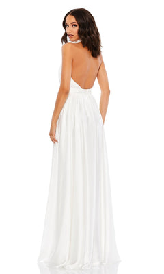 A woman stands against a white background, looking over her shoulder in the High-Neck Halter Formal Dress: Mac Duggal 49333—a floor-length, open-back evening gown.