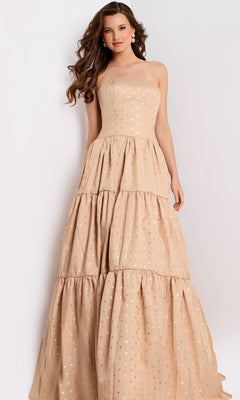 A woman stands against a plain background wearing the Jovani 49341 long prom dress in gold, featuring a strapless design with subtle polka dots and tiered layers.
